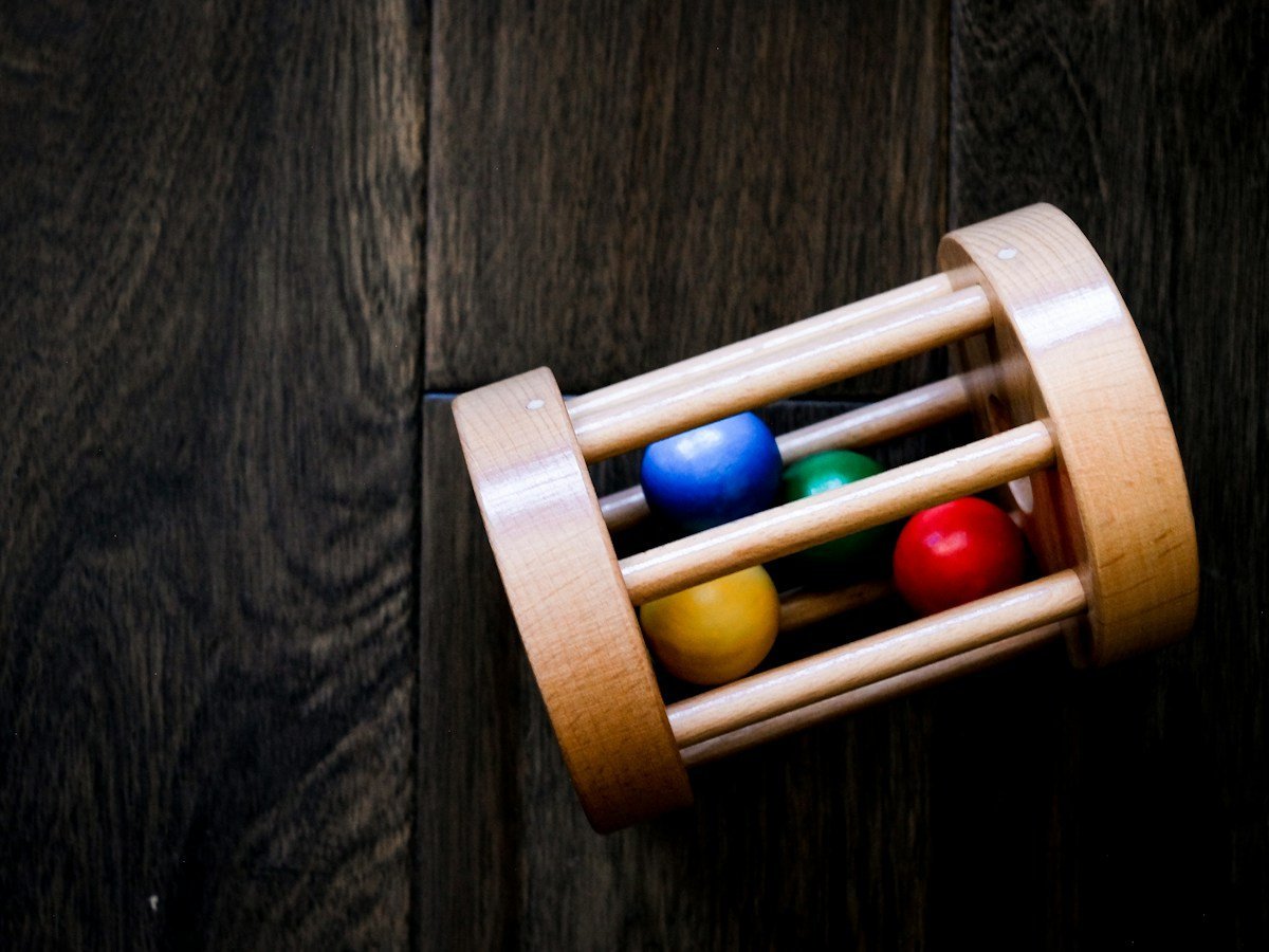 Rollende Rassel aus Holz mit bunten Kugeln im Inneren